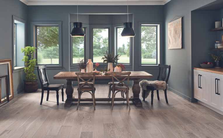gray washed mid tone hardwood floor in dining room with dark accent walls